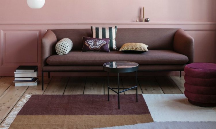 UN SALON DOTE DE MEUBLE ET TAPIS EN HARMONIE AVEC LES MURS DE COULEUR TERRACOTTA